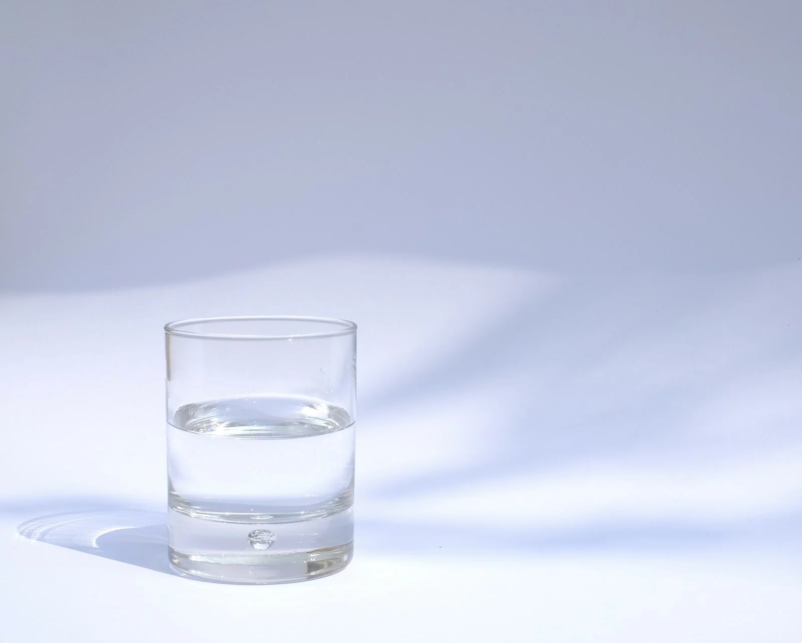 A clear glass of water on a pale table in soft light