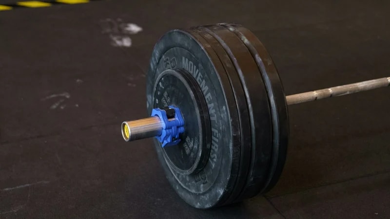 A loaded barbell resting on a black gym floor