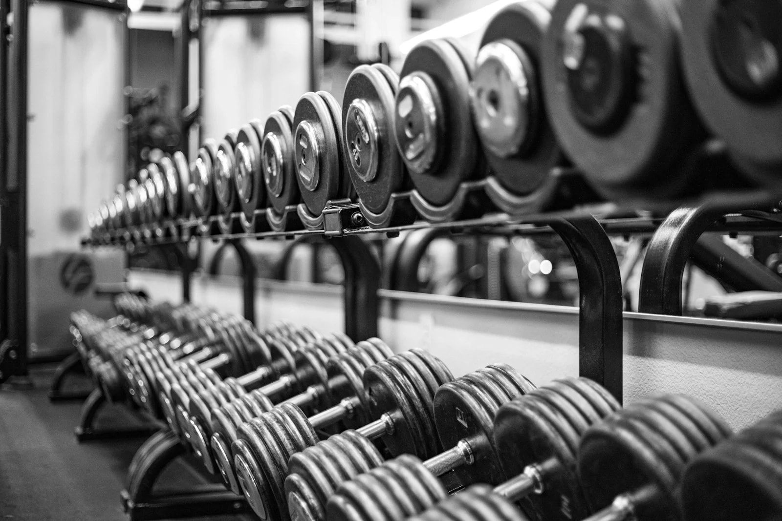 A black and white photo of long rows of dumbbells on gym racks
