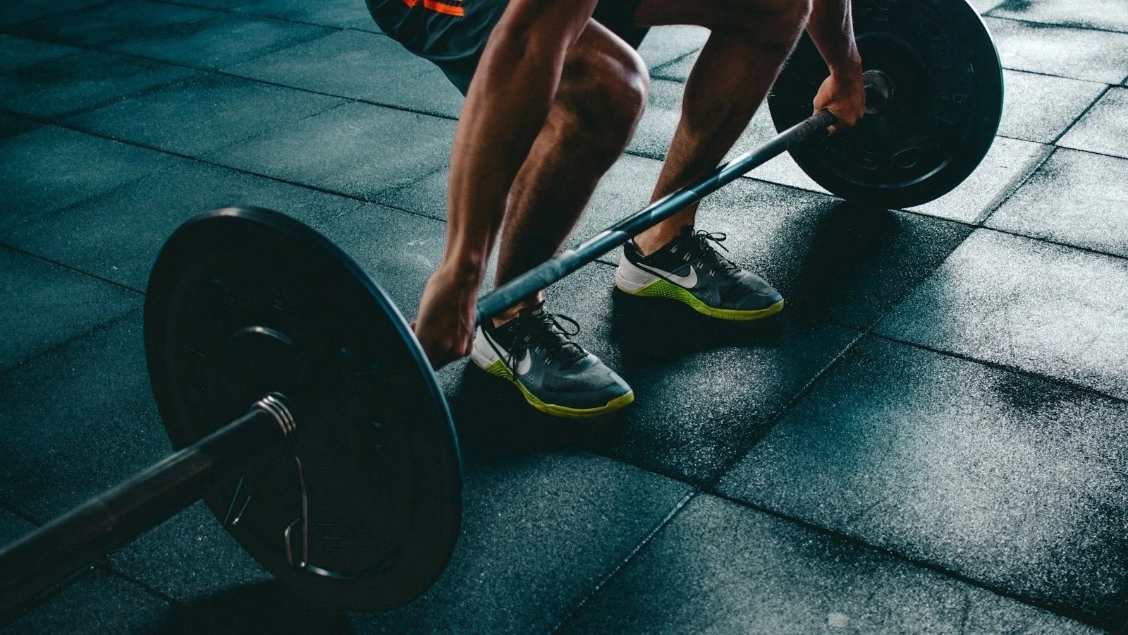 Close-up of hands gripping a loaded barbell on a gym floor before a deadlift
