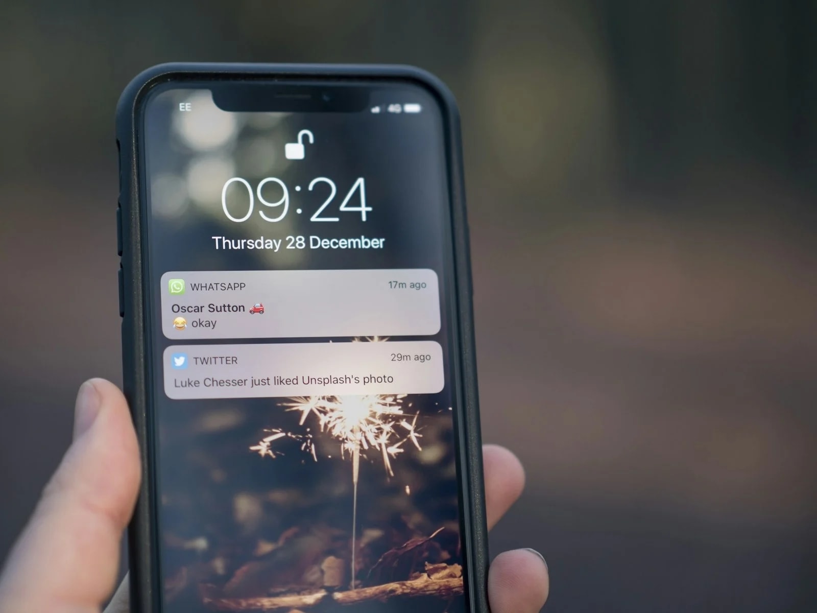 A hand holding a phone with notifications on the lock screen