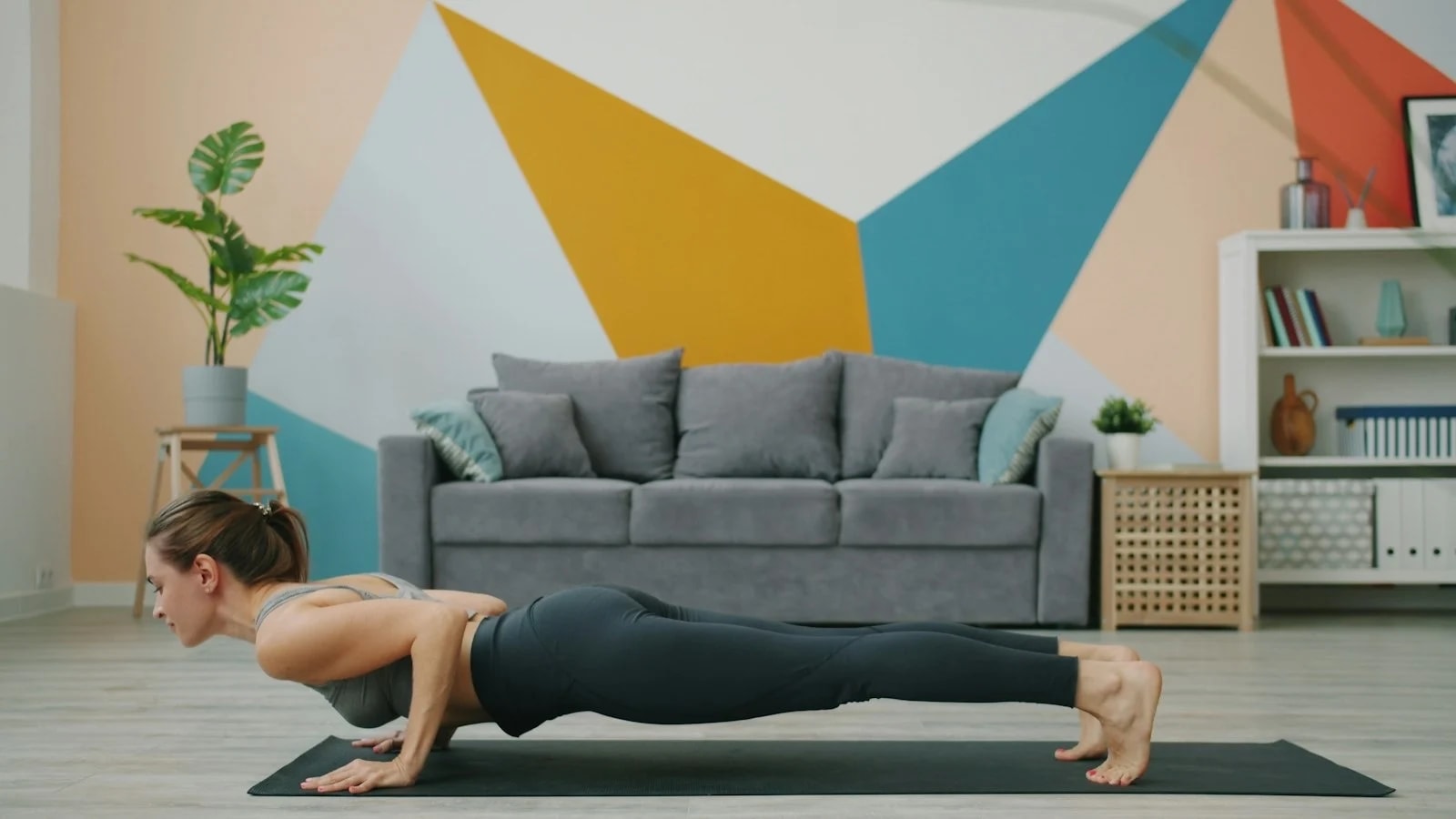 A woman doing a push-up on a yoga mat in a living room