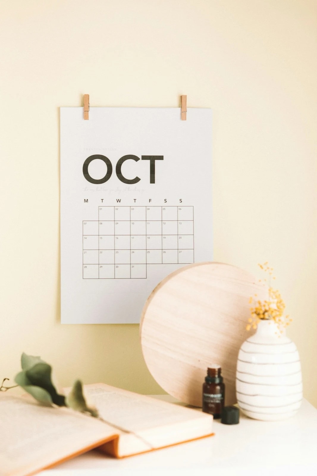 A paper calendar for October pinned to a pale wall