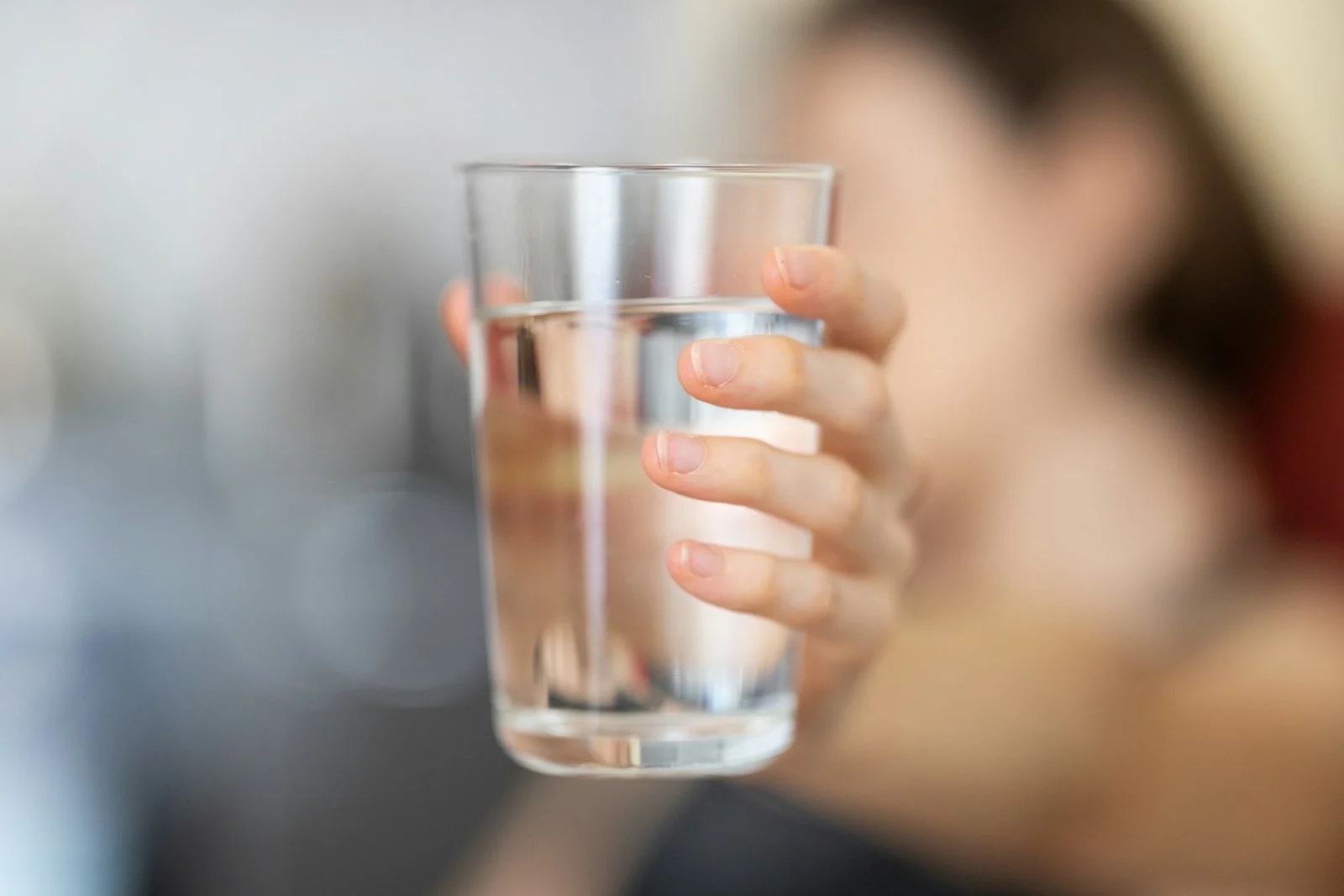 A hand holding up a clear glass of water